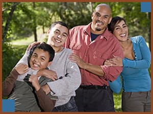 Happy family of four smiling and hugging | Estate Planning for Blended Families | The TGQ Law Firm | Ann Arbor, MI