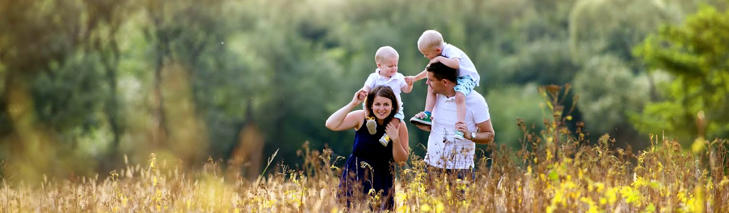 Family in a field with children on their shoulders | Michigan Estate Planning Attorney | The TGQ Law Firm | Ann Arbor, MI