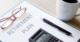 Notebook With The Title Retirement Planning on it on a Desk With a Pair of Glasses, Calculator, Pen, and Cup of Coffee | Common Mistakes In Retirement | The TGQ Law Firm